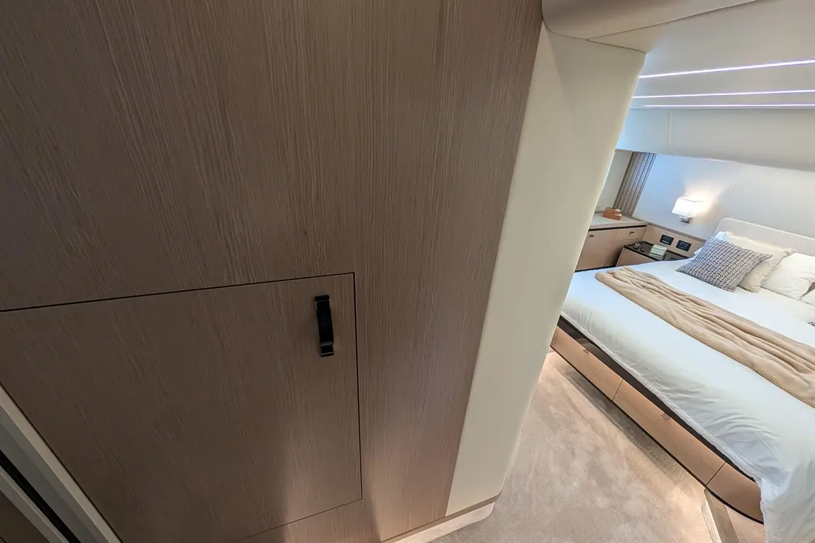 Modern bedroom interior featuring a bed with a beige throw, wooden storage units, and a sleek wardrobe.